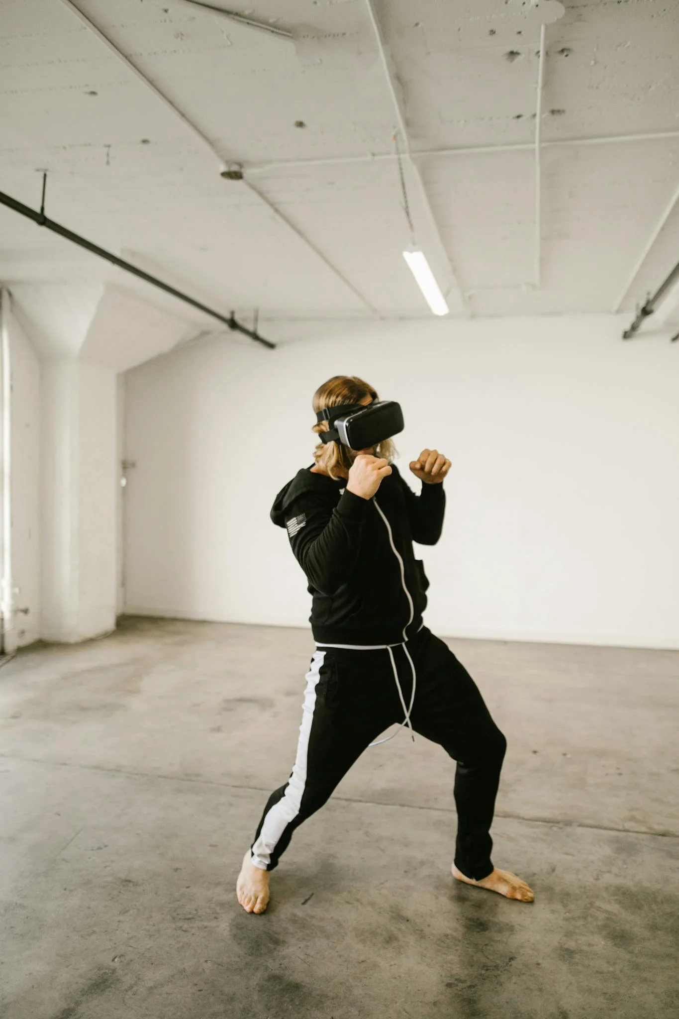 Adult man using VR headset in an empty room for a fun and immersive experience.