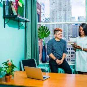 Business meeting between two colleagues in a modern office with a city view.
