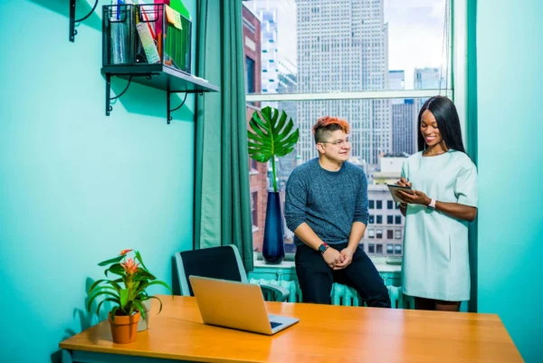 Business meeting between two colleagues in a modern office with a city view.